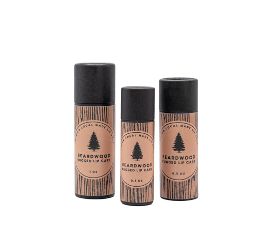 Three tubs of Beardwood Beard Oil lip balm are shown in wood-styled tubes and named Rugged Lip Care. The Beardwood Beard Oil logo in on the front.