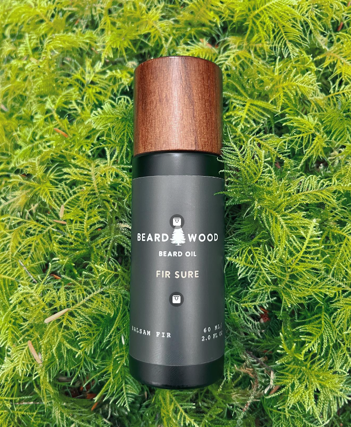 Beardwood Beard Oil sits on top of fur tree with the product name Fir Sure.
