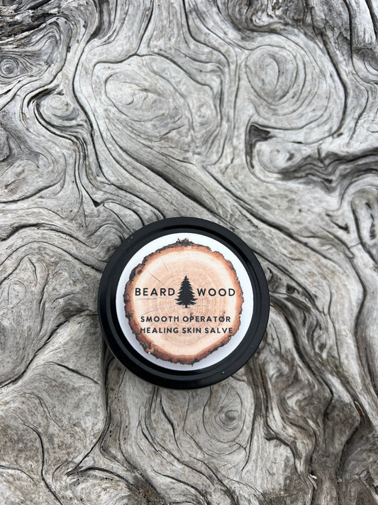 Smooth Operator Healing Skin Salve by Beardwood Beard Oil Co. in Bend, Oregon. The product is in a canister that looks like a tree stump with a black outline. The Beardwood Beard Oil Co. logo is on the front.